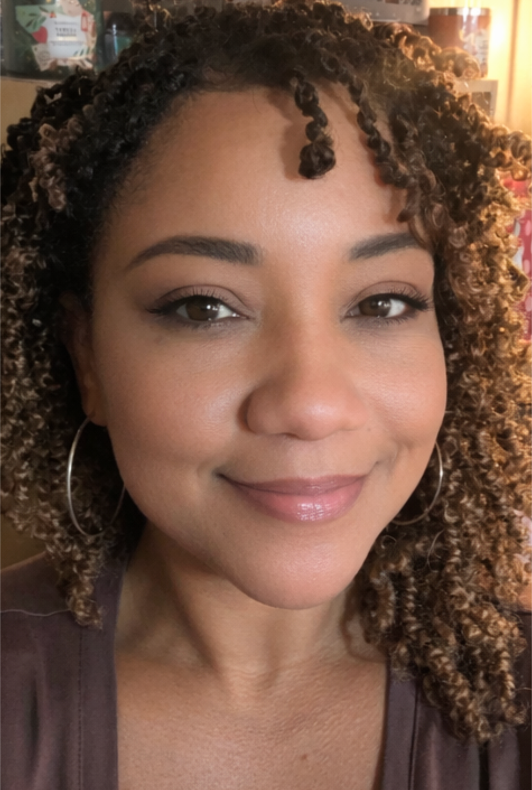 PJ Smith smiling, with curly hair and hoop earrings.